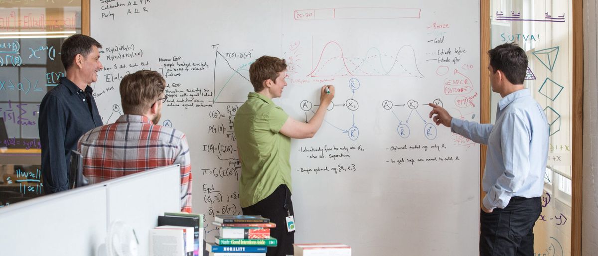 Team discussing equations on a whiteboard