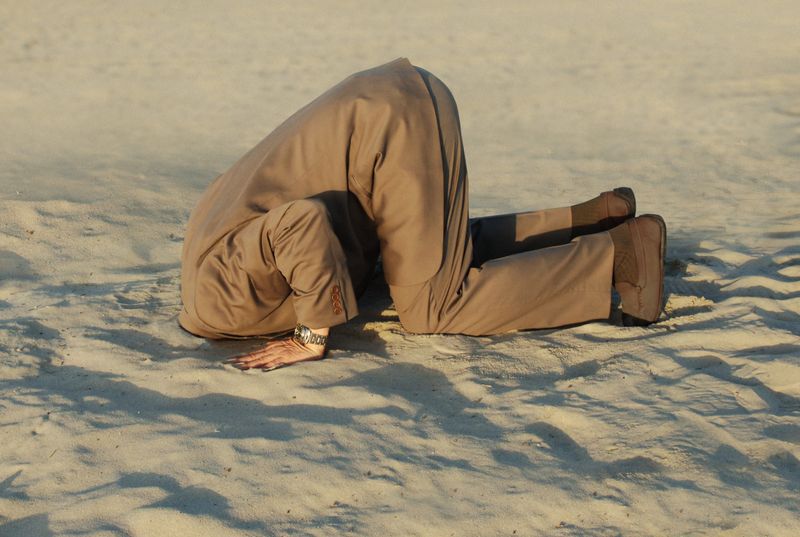 Picture of a person with their head in the sand